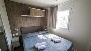 Una camera da letto con un letto, un comodino, un armadio e una finestra con tende.
