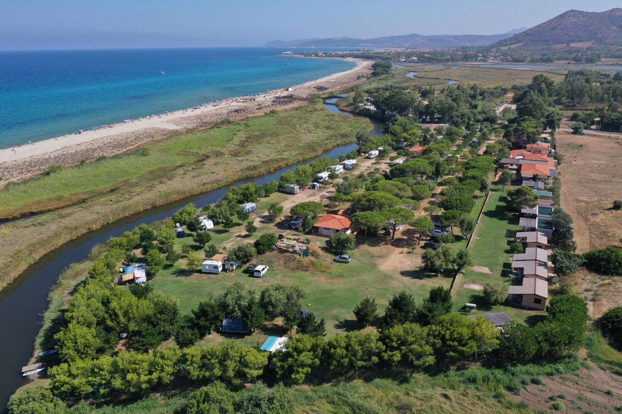 A coastal area with a river, beach, and a row of houses.