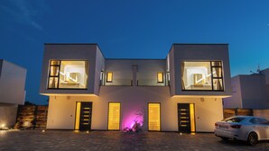 Een modern huis met twee verdiepingen, grote ramen en een oprit.