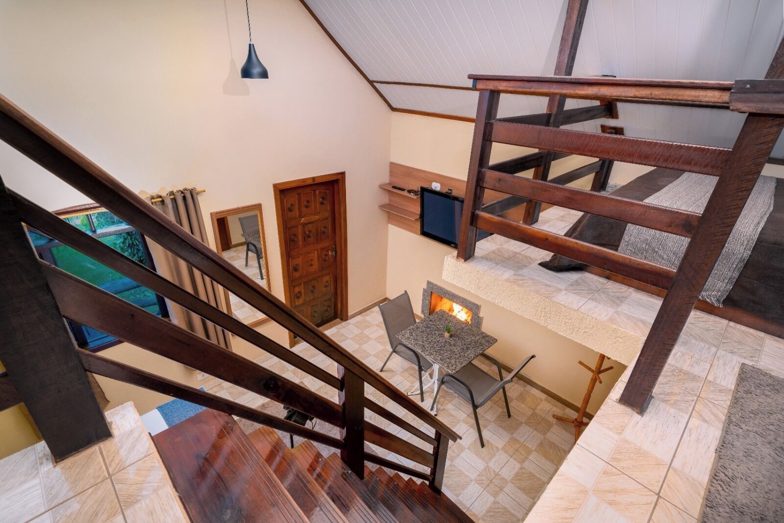 A multi-level interior with a wooden staircase, a small table with chairs, and a fireplace.