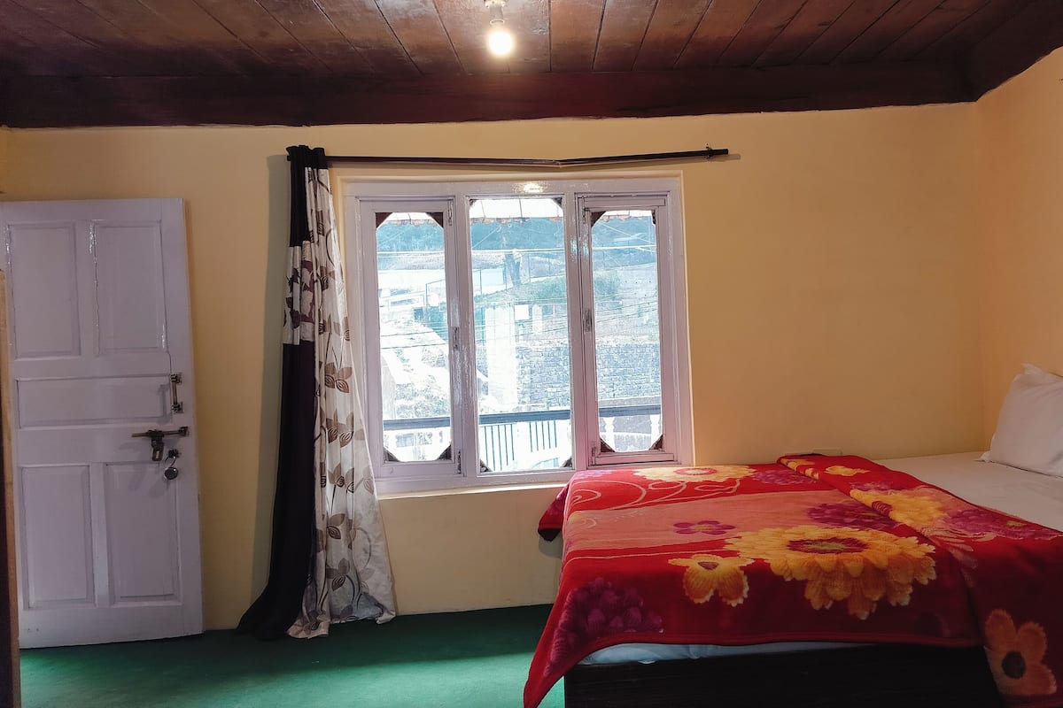 Quarto com cama, janela com cortinas, porta e luminária no teto.