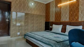 A bedroom with a wooden headboard, a bed with a patterned bedspread, and a blue chair.