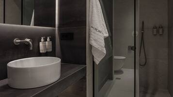 A modern bathroom with a large sink, a glass shower enclosure, and a towel hanging on the wall.