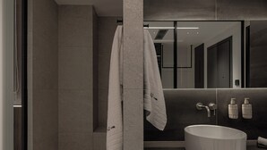 Ein modernes Badezimmer mit einem großen Spiegel, einem runden Waschbecken und einem Handtuch an einem Haken.