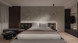 Ein modernes Hotelzimmer mit einem großen Bett, Nachttischen, einer kleinen Sitzecke und einem Kleiderschrank.