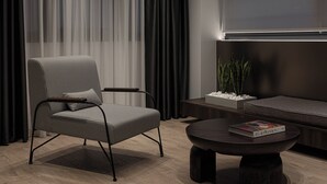 Ein modernes Wohnzimmer mit einer Couch, einem runden Couchtisch, einem Sessel und einem Fernseher.