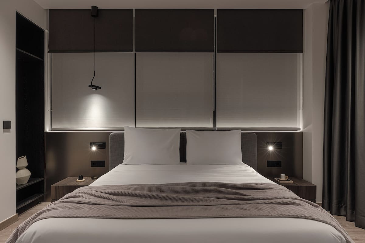 Un dormitorio moderno con una cama grande, mesitas de noche, un armario y un cabecero con iluminación integrada.