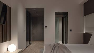 A modern hotel room with a bed, bedside table, and a wall-mounted light fixture.