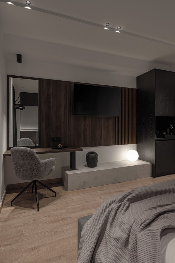 A modern bedroom with a bed, a desk, a chair, a TV, and a bedside table. - Union43 (Ioannina)