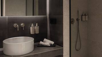 A modern bathroom with a large sink, mirror, and shower.