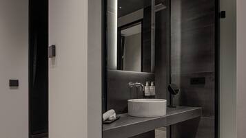 A modern bathroom with a large mirror, a white sink, and a dark countertop.
