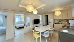 A modern hotel room with a bed, a dining area with a table and chairs, a kitchen, and a bathroom. - Gangnam Style Village (Seoul)