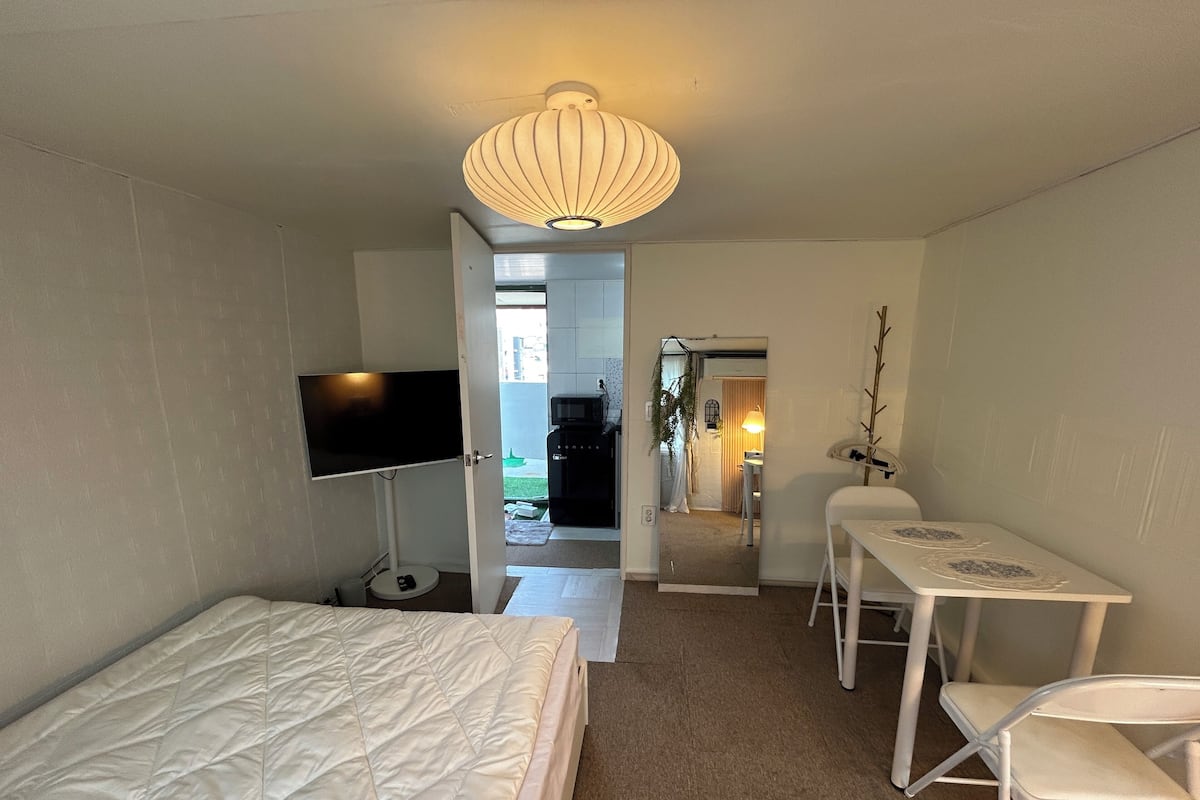 Ein Schlafzimmer mit Bett, Fernseher, Schreibtisch und Stuhl.