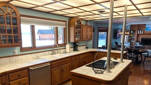 A kitchen with wooden cabinets, a dishwasher, a marble countertop, and a view of the outdoors. - NEW!  The Lighthouse - Large Family-Friendly and Dog-Friendly Home on Big Platte Lake with Central A/C! (Beulah)