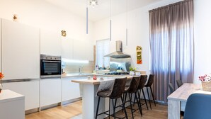 Uma cozinha moderna com uma ilha central, banquetas de bar e uma mesa de jantar.