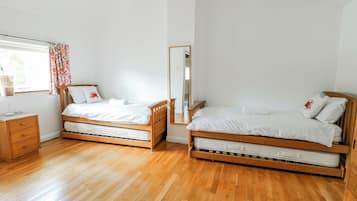 Une chambre à coucher avec deux lits en bois, une table de chevet, un miroir et une fenêtre avec des rideaux.