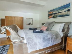Un dormitorio con una cama grande, un armario de madera, un espejo y un cuadro en la pared.