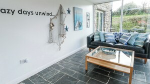 A modern living room with a black leather sofa, a glass coffee table, and a wall with a decorative net and star.