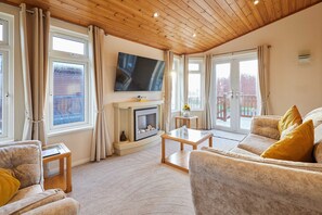 A cozy living room with a fireplace, comfortable seating, and large windows. - Host Stay Mandarin Lodge (Malton)