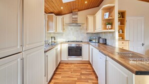 A modern kitchen with white cabinets, a wooden countertop, and a built-in oven. - Host Stay Mandarin Lodge (Malton)