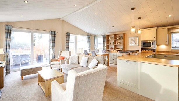 A spacious living area with a sofa, coffee table, and a kitchen with a sink and cabinets. - Host Stay Little Gem Lodge (Malton)