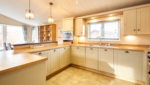 A modern kitchen with white cabinets, a central island, a microwave, and pendant lighting. - Host Stay Little Gem Lodge (Malton)
