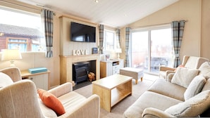 A spacious living room with a fireplace, comfortable seating, and a large TV. - Host Stay Little Gem Lodge (Malton)