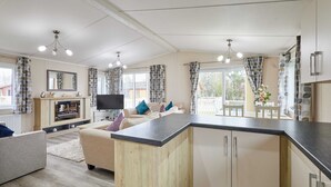 A modern kitchen with a central island, wooden cabinets, and a built-in TV. - Host Stay Rowan Lodge (Malton)
