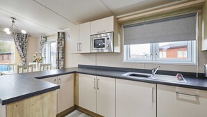 A modern kitchen with a built-in microwave, a sink, and wooden cabinetry. - Host Stay Rowan Lodge (Malton)