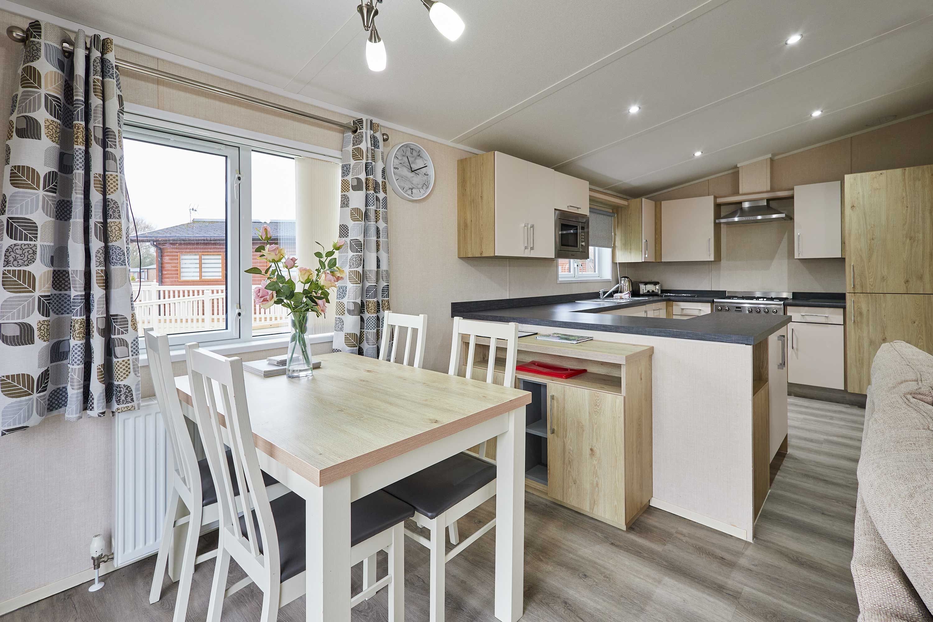 Une cuisine moderne avec un coin repas, des meubles en bois et une horloge au mur.