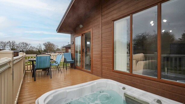 A wooden deck with a hot tub, outdoor seating, and large windows. - Host Stay Rowan Lodge (Malton)