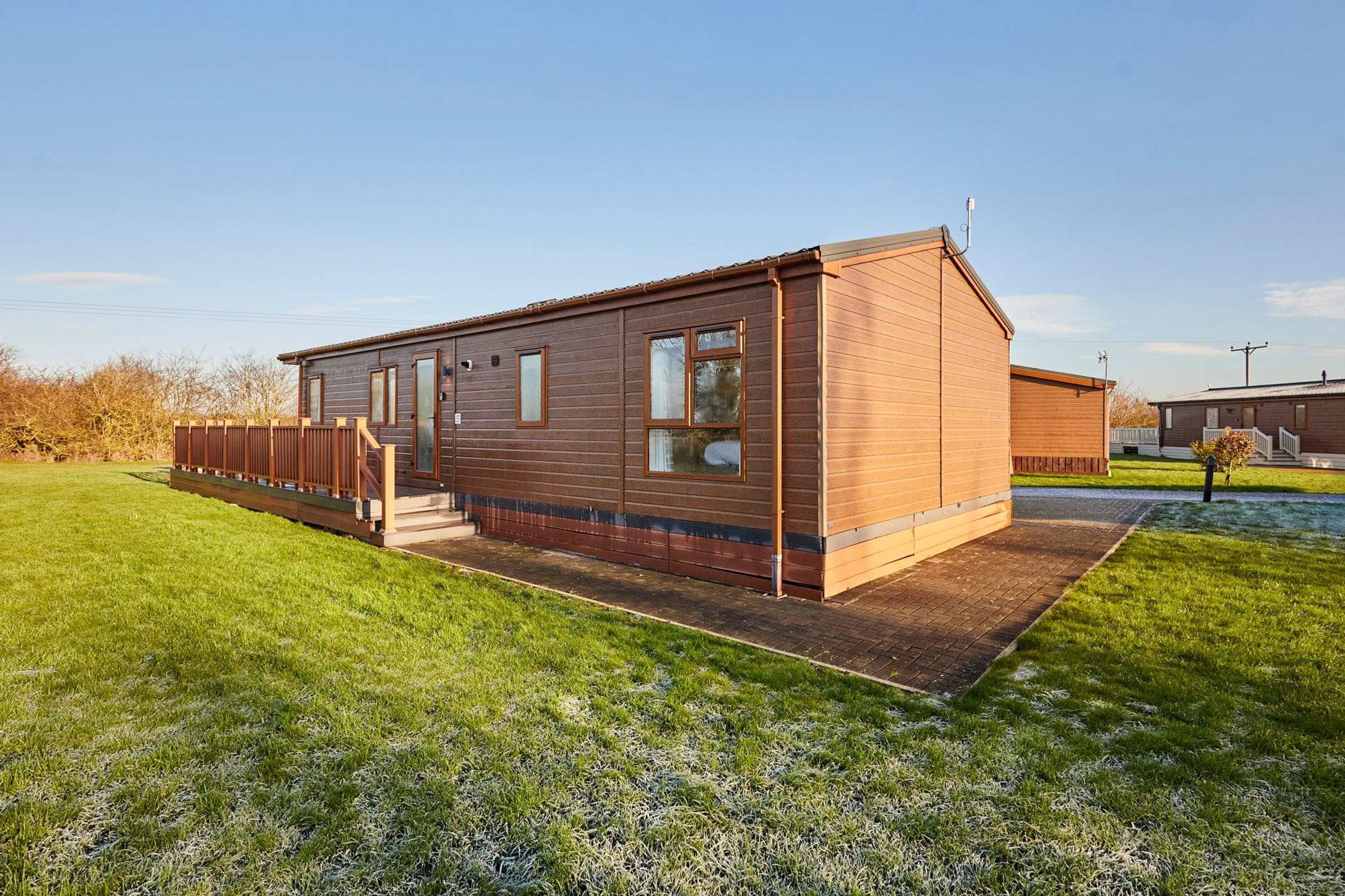A single-story wooden building with a porch, a fenced yard, and a clear sky.