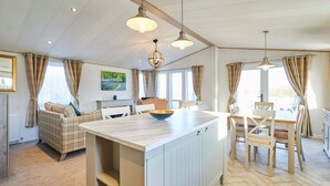 A spacious living area with a large island, a sofa, and a dining table. - Host Stay Hedgerow Lodge (Malton)