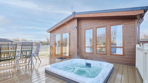 A wooden deck with a hot tub, outdoor seating, and large windows. - Host Stay Hedgerow Lodge (Malton)