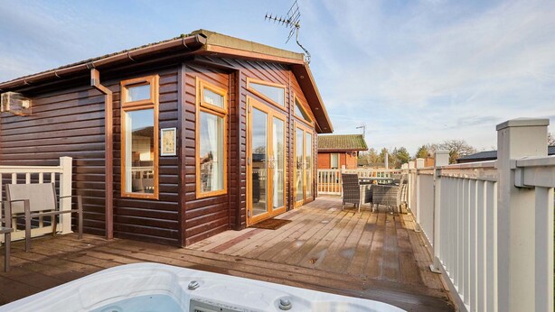 A wooden cabin with a hot tub, wooden deck, and a fenced patio area. - Host Stay Crystal Lodge (Malton)