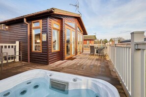 A wooden cabin with a hot tub, wooden deck, and a fenced patio area. - Host Stay Crystal Lodge (Malton)