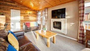A cozy living room with a wooden ceiling, a fireplace, a sofa, and a coffee table. - Host Stay Crystal Lodge (Malton)