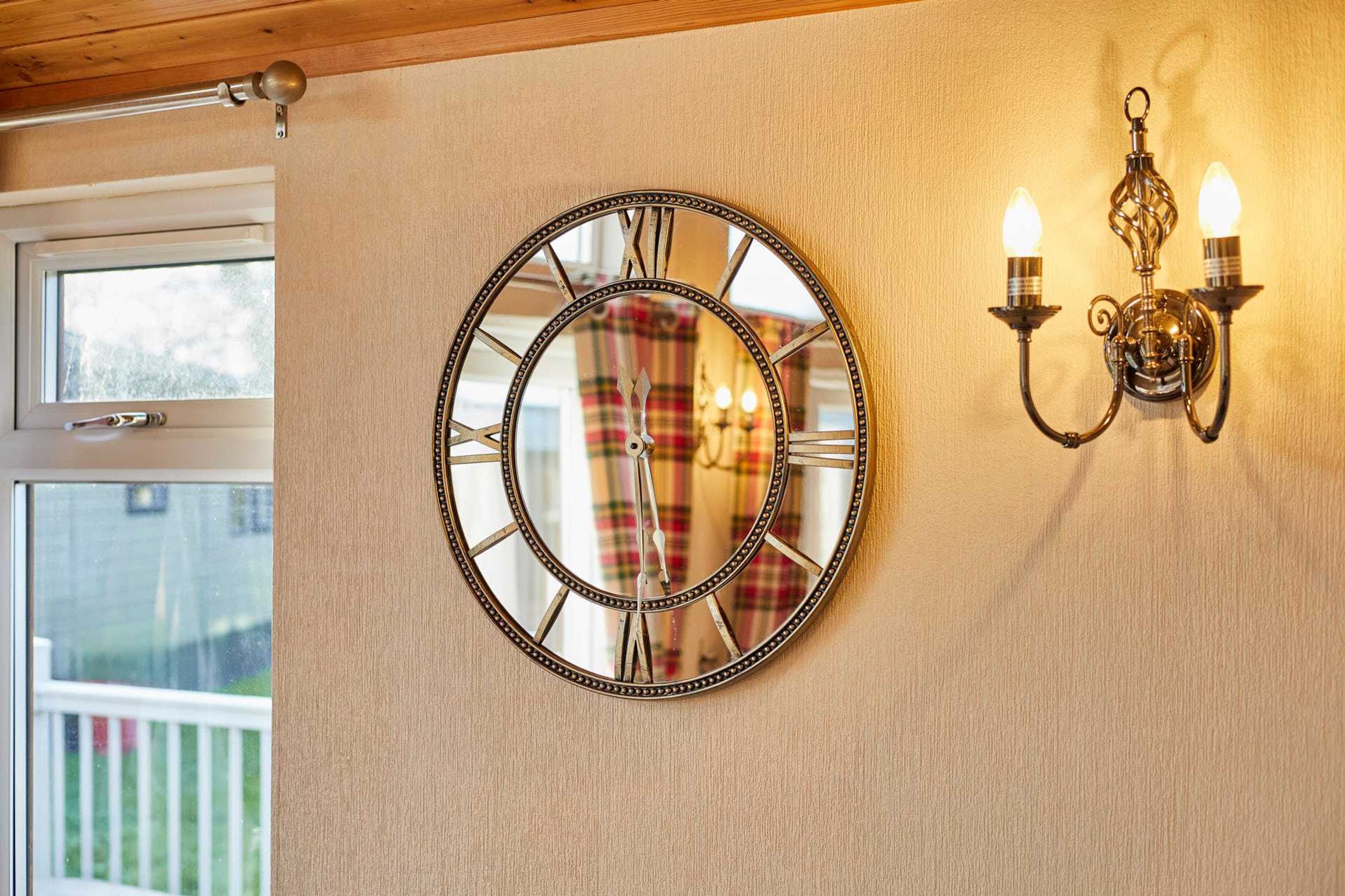 A wall clock with Roman numerals and a wall-mounted light fixture with two candles.