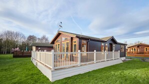 A two-story log cabin with a deck and a fenced patio area. - Host Stay Crystal Lodge (Malton)