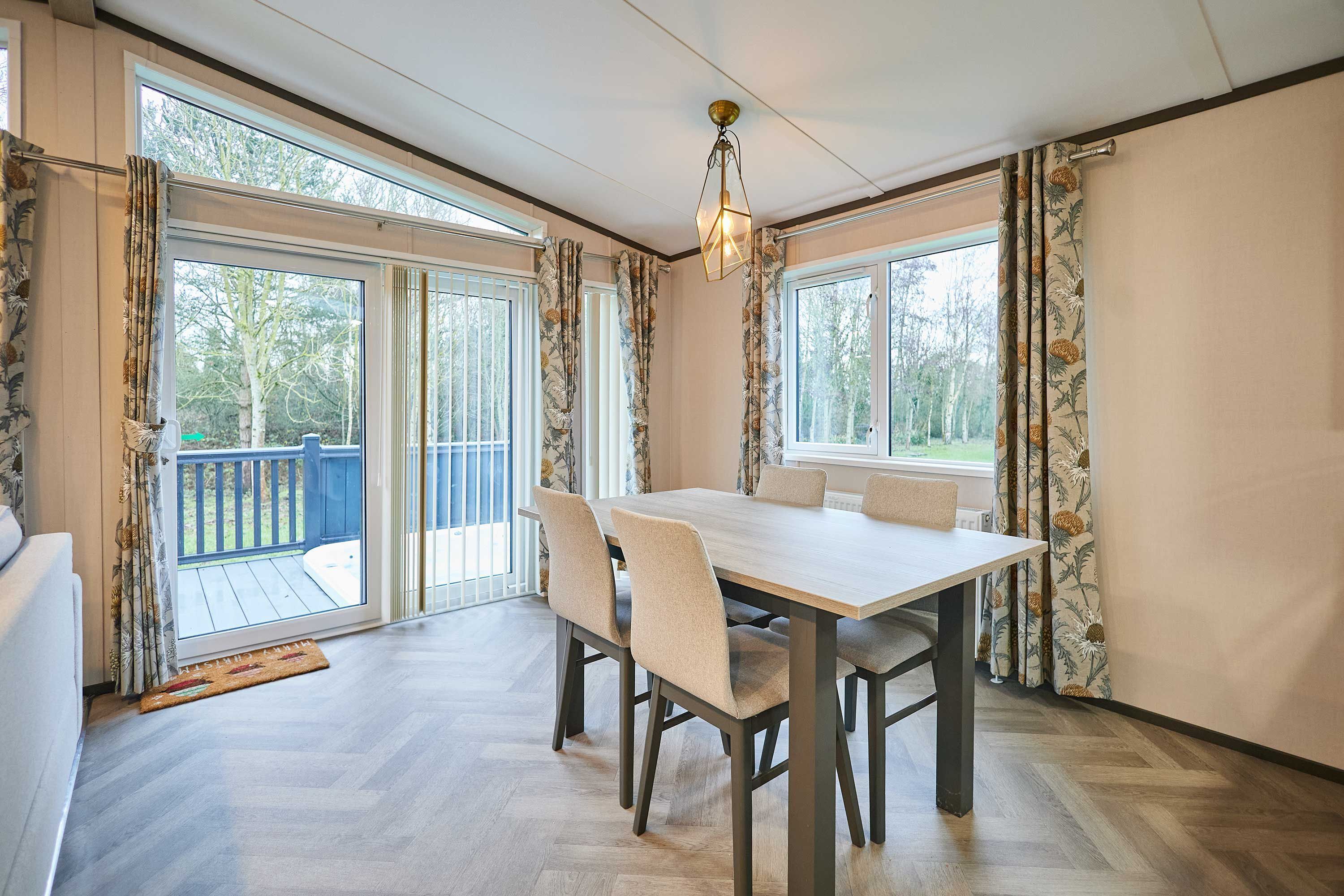 A dining area with a table and chairs, large windows, and a view of the outdoors.