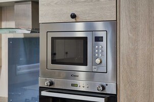 Una cocina moderna con horno microondas integrado, un reloj digital y un panel de control.
