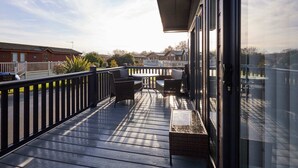 A covered outdoor area with a table and chairs, a white fence, and a view of houses in the background. - Host Stay Penny Lodge (York)