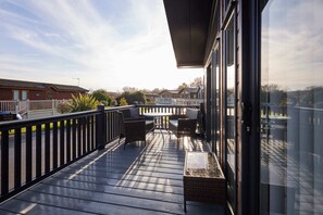 A covered outdoor area with a table and chairs, a white fence, and a view of houses in the background. - Host Stay Penny Lodge (York)