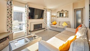 A living room with a fireplace, sofa, and television. - Host Stay Penny Lodge (York)