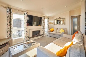 A living room with a fireplace, sofa, and television. - Host Stay Penny Lodge (York)