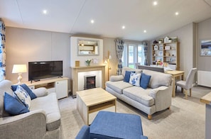 A modern living room with a television, sofa, and a fireplace. - Host Stay The Haven Lodge (York)