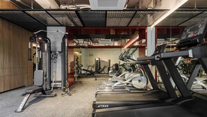 Un gimnasio con cintas de correr, máquinas de pesas y un banco.