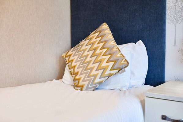 A neatly made bed with white bedding and a single decorative pillow with a zigzag pattern. - Host Stay Deneb Lodge (Malton)