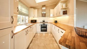 A modern kitchen with white cabinets, a wooden countertop, a built-in oven, and a skylight. - Host Stay Deneb Lodge (Malton)