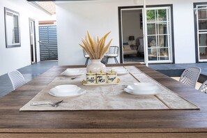 A dining table set with white plates, silverware, and a vase with dried plants. - 5BR Family Retreat Spa, Sauna, Gym Miranda sleep12 (Miranda)